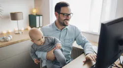 Man at home office desk holding child