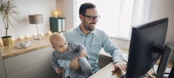 Man at home office desk holding child Man at home office desk holding child