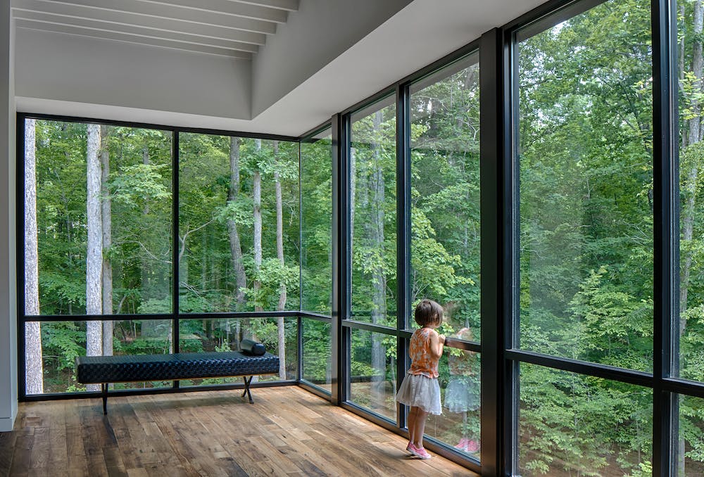 Girl looking into the woods from floor to ceiling windows