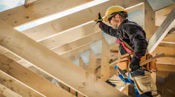 A custom home builder works on the roof of a house