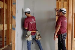 Two Members Of Prestige Custom Builders Wearing Hard Hats And Maroon T Shirts Install Dens Shield® Tile Backer In A Home Two Members Of Prestige Custom Builders Wearing Hard Hats And Maroon T Shirts Install Dens Shield® Tile Backer In A Home