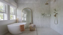 Shown is a wet room with big windows, an oversized gold framed mirror, freestanding tub and brass shower fixtures. Shown is a wet room with big windows, an oversized gold framed mirror, freestanding tub and brass shower fixtures.