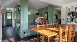 A green-built in in the center of a living room features shelving and a day bed A green-built in in the center of a living room features shelving and a day bed