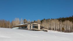 A contemporary home sits in a snowy hillside. A contemporary home sits in a snowy hillside.