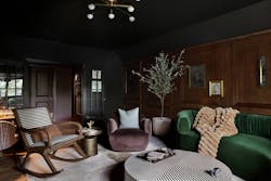 Moody living room with dark wood wall paneling and jewel-toned furniture Moody living room with dark wood wall paneling and jewel-toned furniture