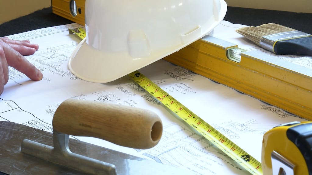 A closeup of a floor plan and tools used for a renovation at a time when home building pros feel cautious about the economy and their business.