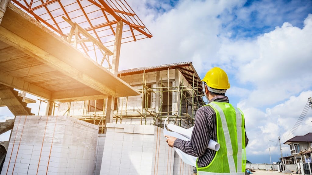 Home builder looks over plans at a jobsite as wage growth for residential professionals slows.