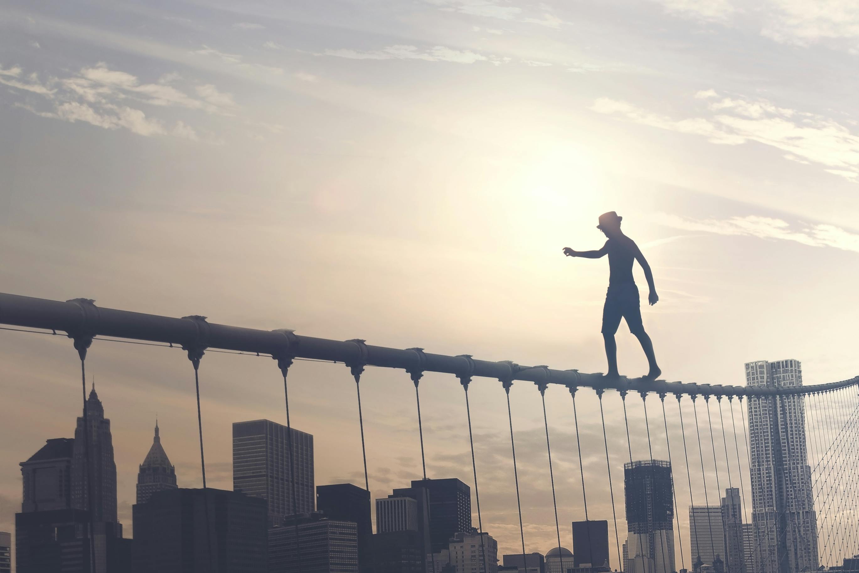 Man walking 'tightrope' along the top of a bridge | Abstract business risk