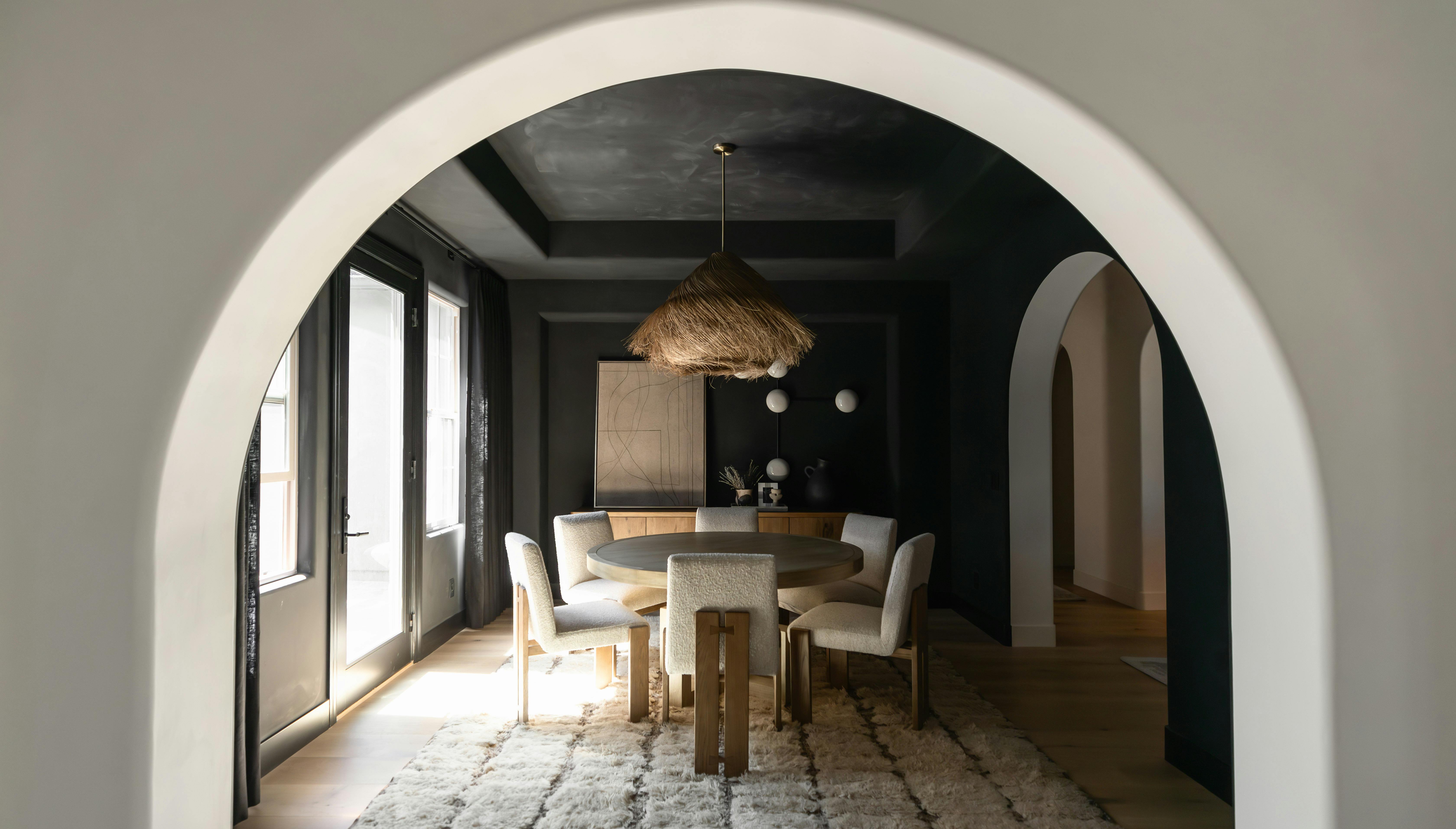 Interior arch leading to a dining room with walls and ceiling in black limewash | wabi sabi styled home in Scottsdale
