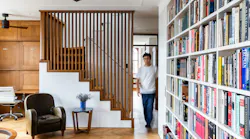 Blurrred image of someone walking into a living room, where a staircase featured sliding louvered doors to create privacy when needed
