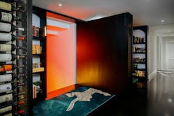 A hidden bookcase door is swung open to reveal the orange glow from the newly built subterranean wine room below A hidden bookcase door is swung open to reveal the orange glow from the newly built subterranean wine room below