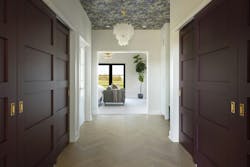 The primary suite closet is a deep eggplant-painted corridor, with a wallpapered ceiling and herringbone floors. The primary suite closet is a deep eggplant-painted corridor, with a wallpapered ceiling and herringbone floors.