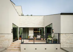 The home's exterior features a hand-raked stucco and limestone with black detailing for contrast. The home's exterior features a hand-raked stucco and limestone with black detailing for contrast.