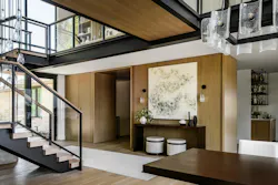 *The catwalk passes above the double-height entry on its way to the office, its steel edge beam matching the stair's stringers below.*