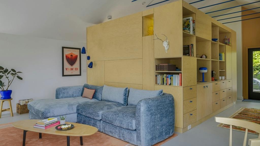 A custom shelving unit in the middle of this ADU optimizes both storage and privacy in a small space.