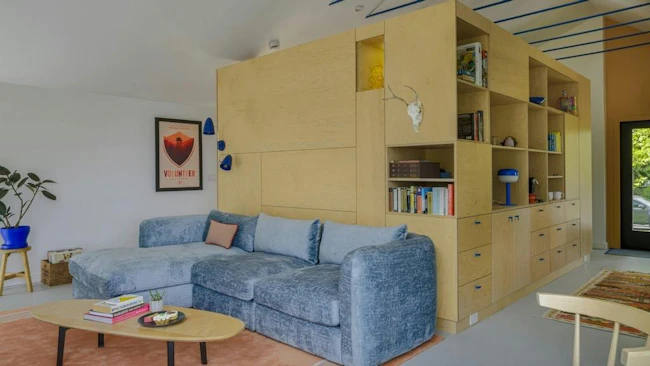 A custom shelving unit in the middle of this ADU optimizes both storage and privacy in a small space.