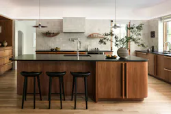 The kitchen features a number of custom details, including a curved island, elongated cabinet pulls, and handmade tiles.